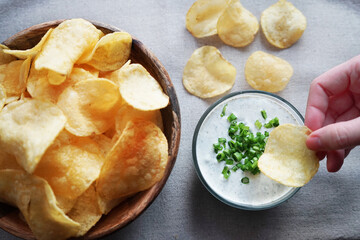 Potato chips with sauce with herbs on a gray background