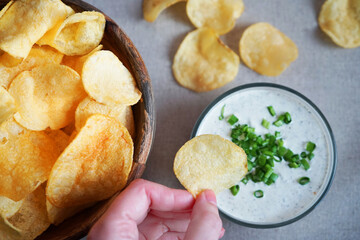Potato chips with sauce with herbs on a gray background