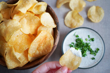 Potato chips with sauce with herbs on a gray background