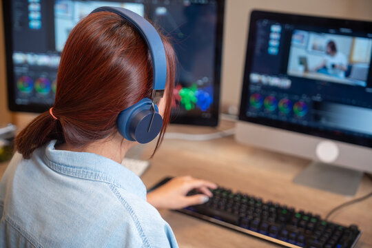Female asian freelancer editing video for customer or travel blogger in program on computer while sitting at the table and working at home