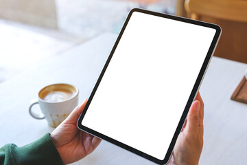 Mockup image of a woman holding digital tablet with blank white desktop screen in cafe