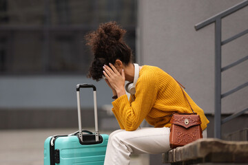 Being late. Frustrated woman with suitcase sitting on bench outdoors, space for text