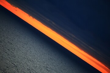 Creative diagonal shot of orange horizon between dark clouds and Baltic sea - 712234269