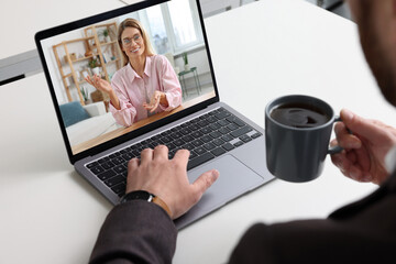 Man having video chat with consultant via laptop at white table, closeup