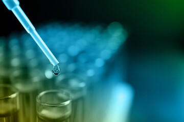 Dripping reagent into test tube with sample, closeup. Color toned