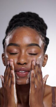 Black woman, face wash and skincare for hygiene or grooming on a gray studio background. Closeup of African female person cleaning, facial treatment or soft scrub in cleanse, hydration or exfoliation