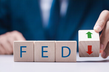 Businessman stack wooden cubes with FED word and up or down arrow icon. Fed rate hike concept to curb inflation. - obrazy, fototapety, plakaty