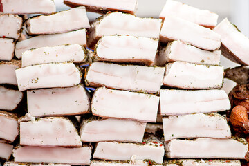 Big pieces of lard or bacon covered with herbs and spices in a street food market, close up