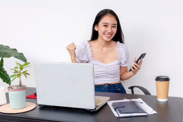 Smiling young woman studying at desk with laptop, phone, and coffee, portraying a productive college student life.