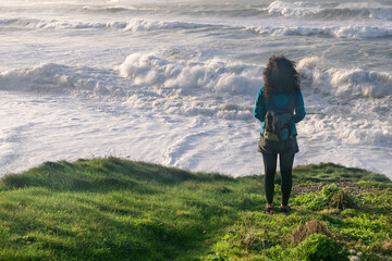 Woman on cliff looking at strong waves