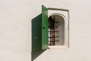 Pskov, Russia, September 6, 2023. Window with bars and shutters in the fortress wall.