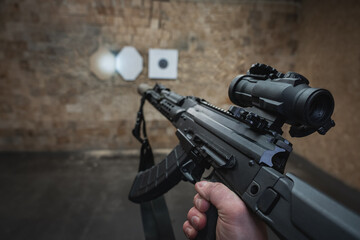 Shooting at a target from a tactical carbine with an optical sight. Photo with a first-person view. - obrazy, fototapety, plakaty
