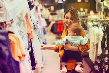 Fototapeta premium Blonde woman with little daughter in clothes store