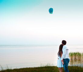 Young couple start a green Chinese sky lantern in the dusk