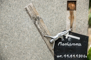 rotten old wooden cross with a metal image of Christ and a tombstone with the inscription "RIP Marianna"
