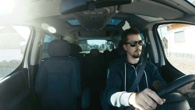 Male driver behind the wheel in car wide shot 4K. Camera on car dashboard with wide view of inside the car and person in focus driving.