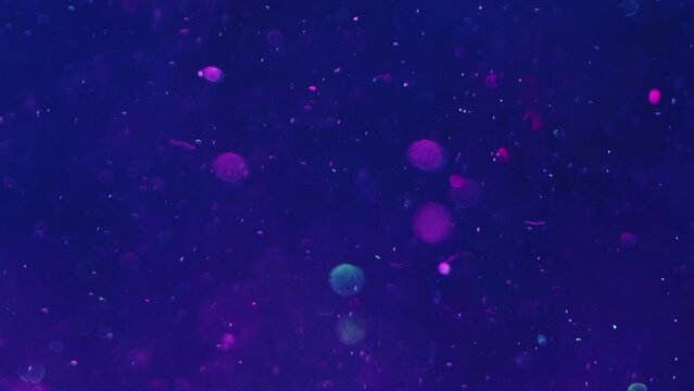 Bokeh lights. Blur shimmering. Water particles flow. Radiant circles floating in dark blue violet liquid with glitter in ocean illusion abstract background art.