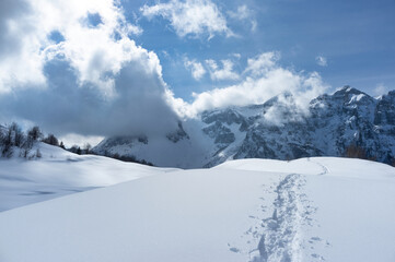 Mountain landscape, completely covered in snow with traces of hikers on the snow