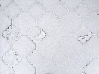 Footpath paved with pavement tiles dusted with snow in park