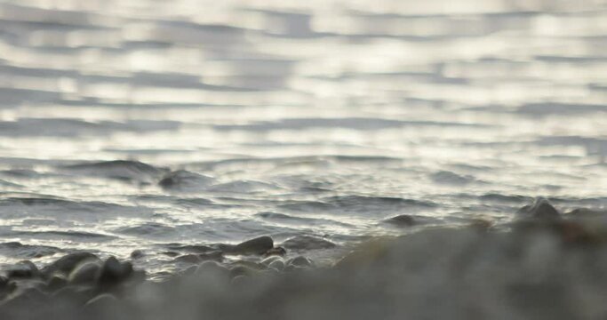 slow motion water texture gently flowing over a pebble on a rocky beach