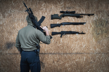 A man in a hood with an AK 12 weapon in his hand is engaged in tactical shooting at a shooting...