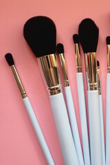 Various different make up brushes on pink background. Top view.