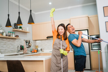 asian couple having fun while cleaning the house together