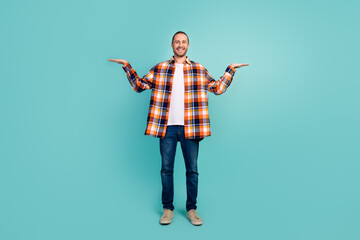 Full length photo of satisfied man wear flannel shirt jeans arms demonstrate objects empty space...