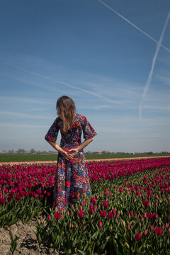 woman in floral dress standing in pink and red tulip field in the Netherlands