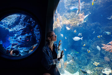 Young woman looking at fishes in oceanarium