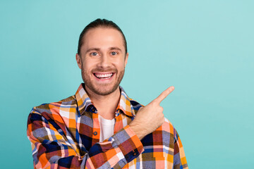 Portrait of pleasant guy with beard long hairdo wear flannel shirt indicating at sale empty space isolated on turquoise color background