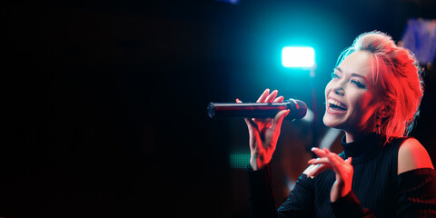 Joy and music. Happy young woman is singing in karaoke nightclub.