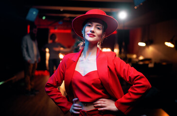 Portrait of young beautiful woman in red hat posing in night club.