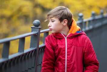 A thoughtful teenage boy walks outside, looks around. Psychological portrait of a teenager.