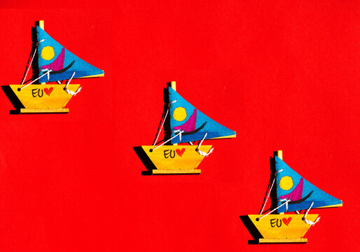 Veleiro em miniatura de madeira, vela de cor azul e fundo vermelho. 