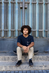 Teen boy sitting on skateboard.