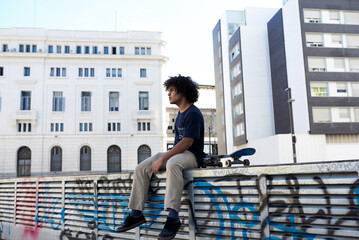 Pensive skateboarder on graffiti block.