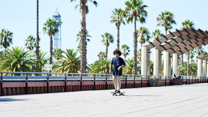 Cool teen boy sliding on skateboard along sunny sidewalk.