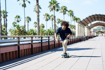 Boy sliding his skateboard along sunny sidewalk.