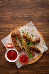 Top view of grilled meat sausages and dips on wooden surface