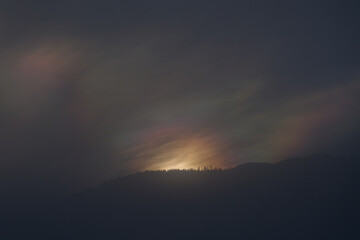 mystical sunrise over the mountains with a colorful light, fog and tree silhouettes