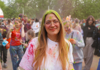Fototapeta premium Holi festival of colors, a young woman celebrates the beginning of spring and showers each other with colorful paints