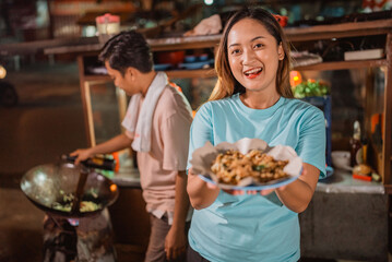 asian woman serving cooked food to her customer