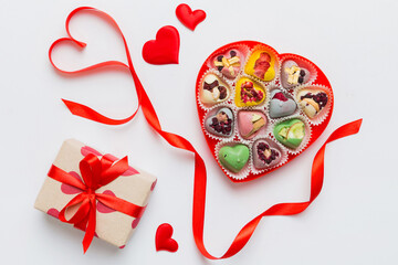 Valentine day composition: sweet candy, with gift boxes with bow and red felt hearts, photo...