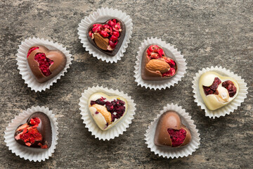 chocolate sweets in the form of a heart with fruits and nuts on a colored background. top view with space for text, holiday concept