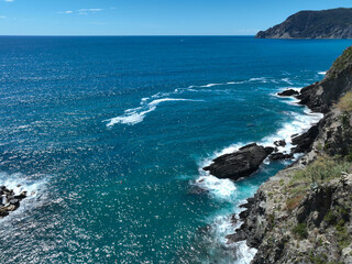Aerial footage of turquoise ocean waters washing rugged, rocky shoreline