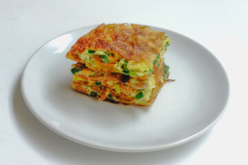 Martabak Telur or Egg Martabak is Savory pan-fried pastry stuffed with egg, meat and spices on white plate isolated on white background . Martabak Telur is one of Indonesia street food