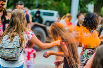 A girl throws orange paint at another girl during the Holi festival