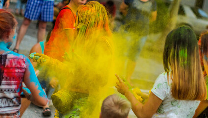 Girls throw a lot of yellow colors at another girl during the Holi festival