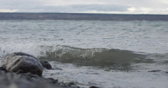 small waves crashing on the shore in a windy lake